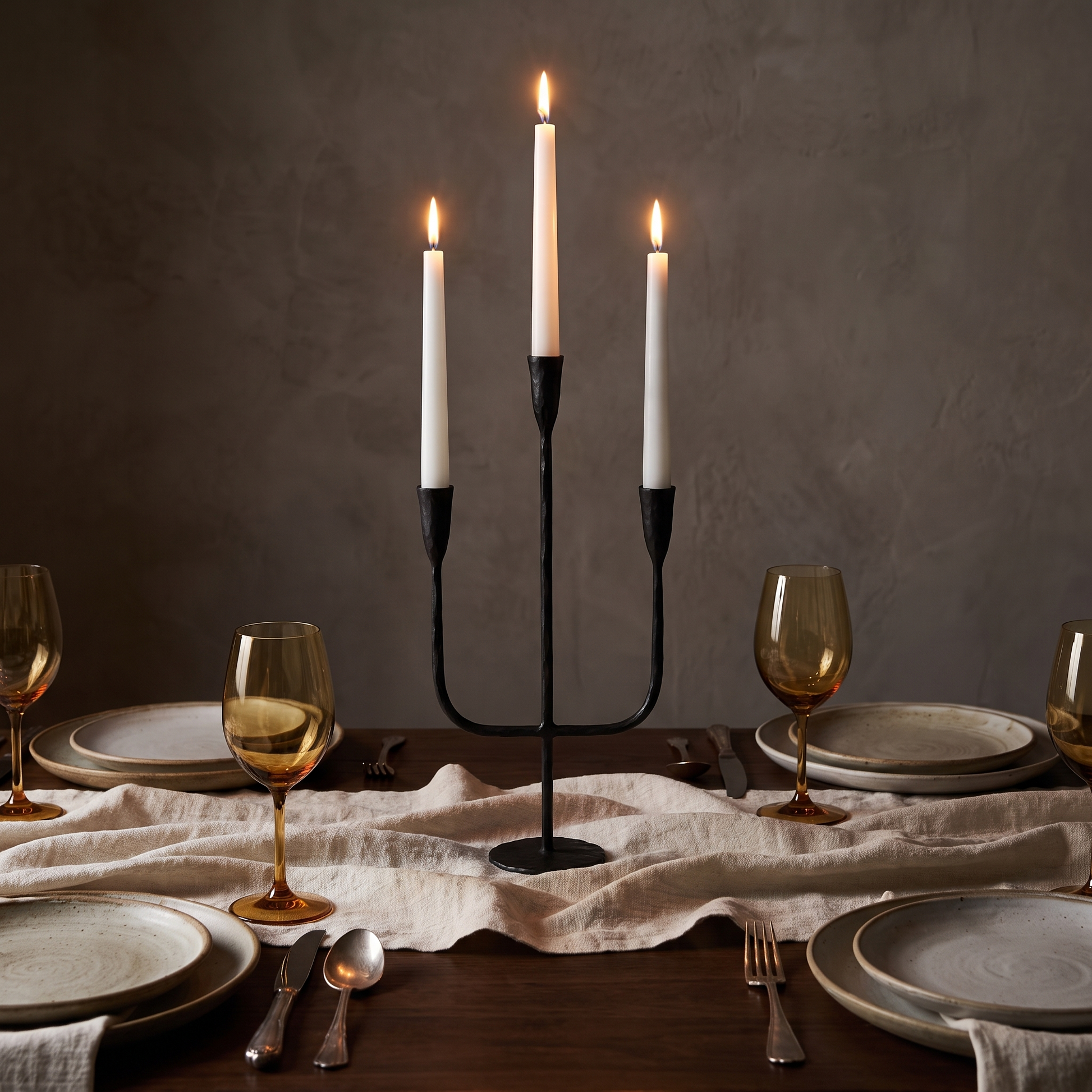 Hand-forged iron candelabra with lit tapers as a dinner table centrepiece