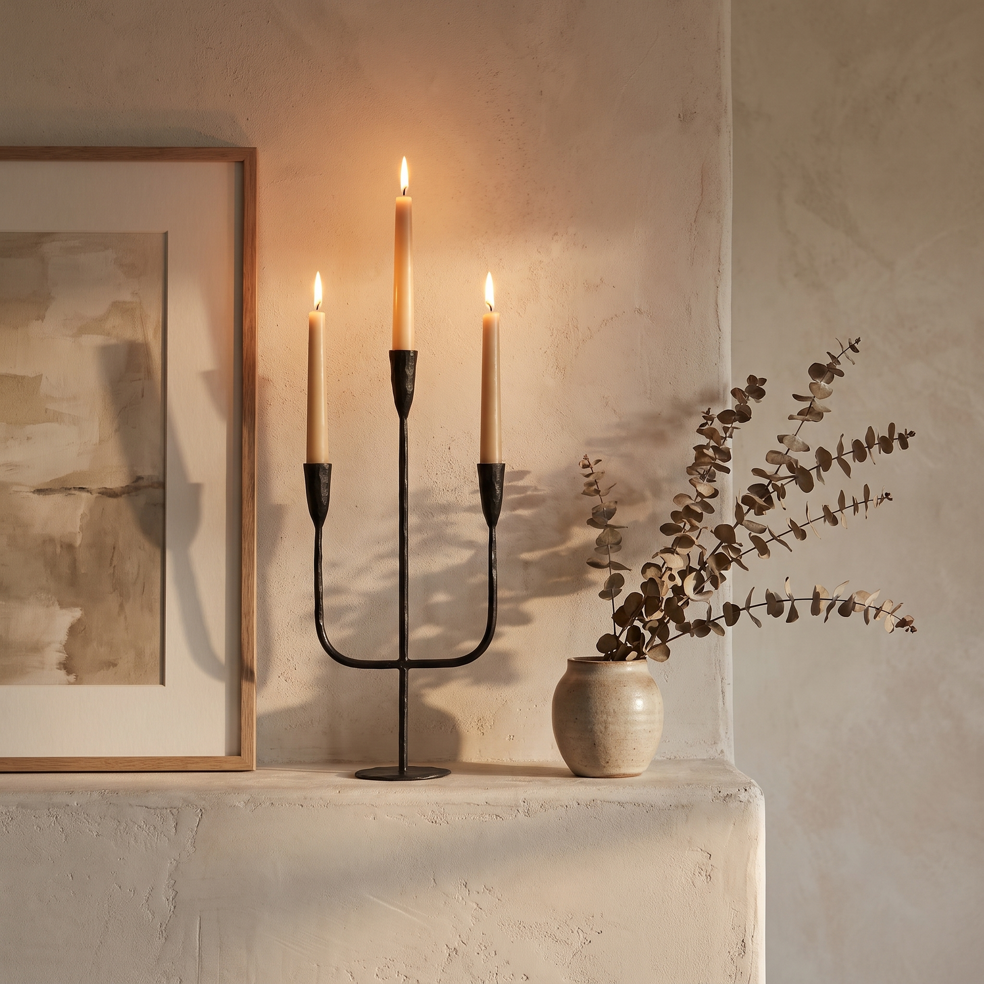 Hand-forged iron candelabra with lit tapers styled on a plaster mantelpiece