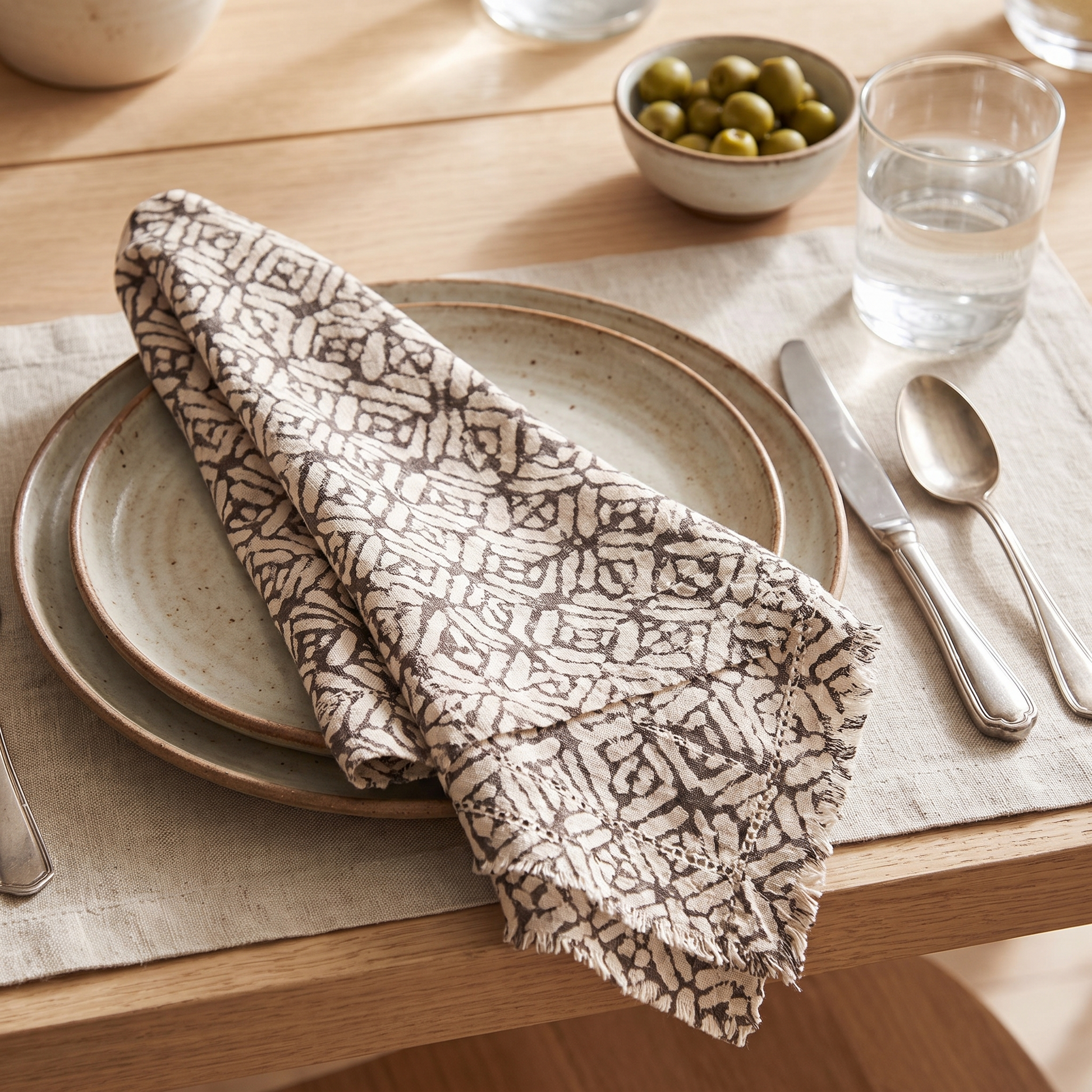 Kleo block printed napkin folded across a plate in a relaxed table setting