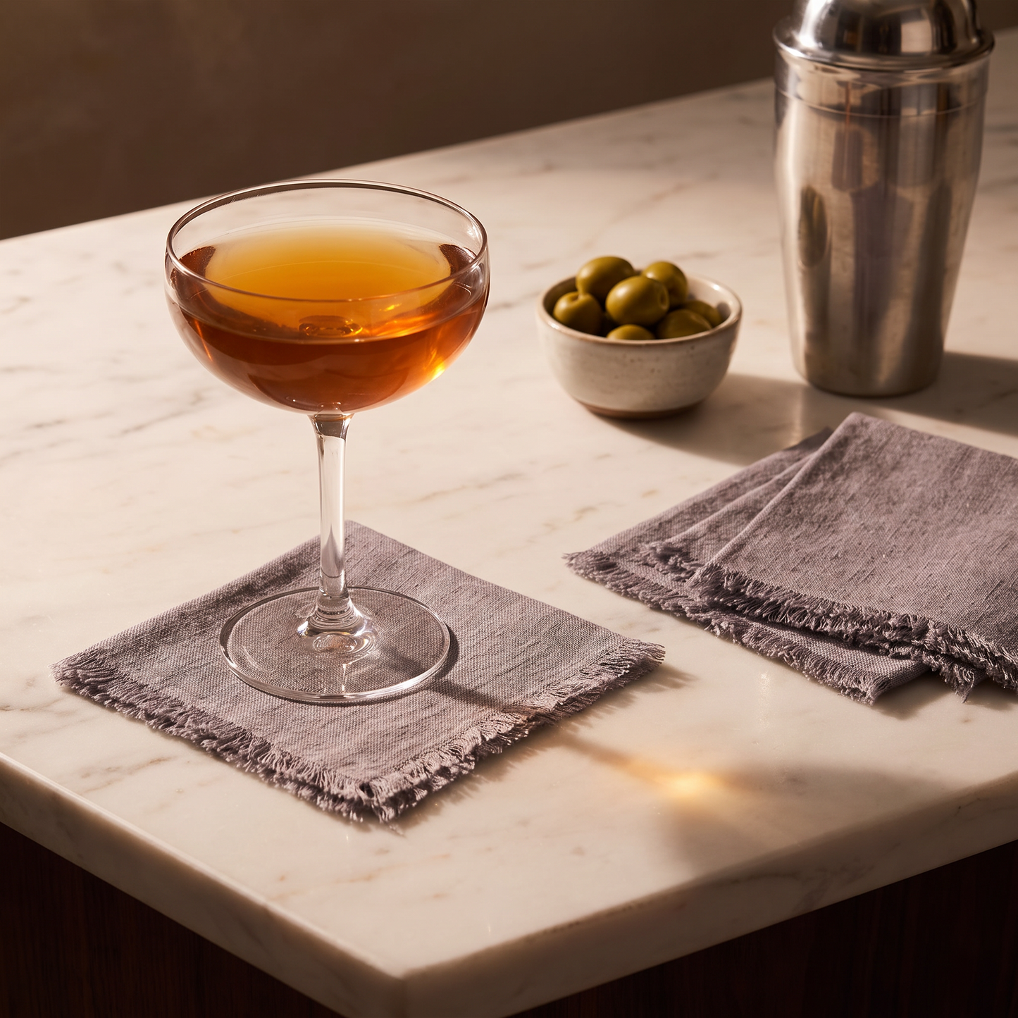 Stone washed linen cocktail napkin under a coupe glass on a marble bar top