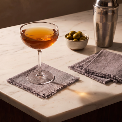 Stone washed linen cocktail napkin under a coupe glass on a marble bar top