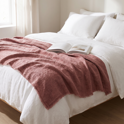 Stone washed linen throw blanket draped across a bed with white linen bedding