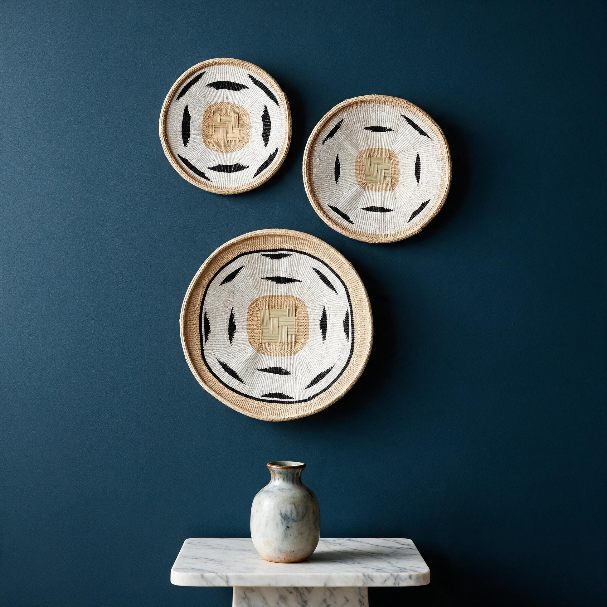Nolyia white flat baskets grouped on a dark wall